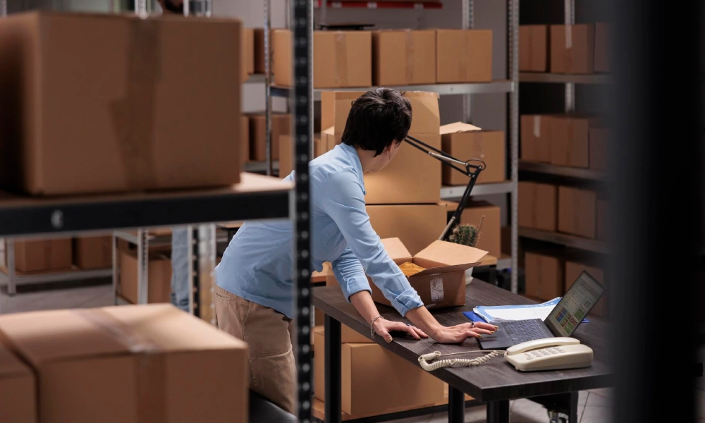 Persona revisando el inventario en un almacén con cajas para controlar el stock de seguridad